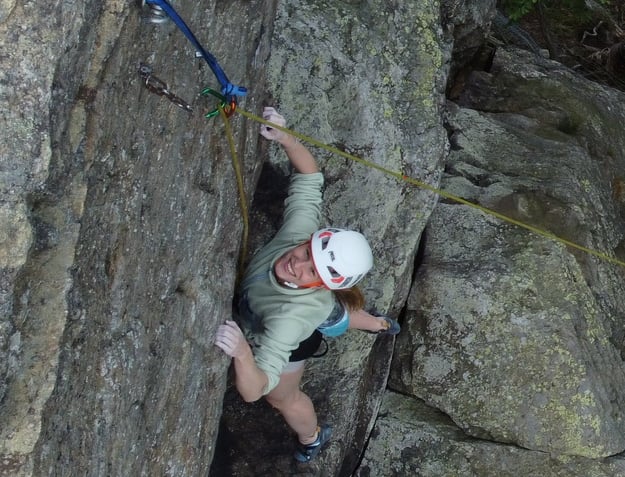 Kletterkursteilnehmerin ist glücklich über geschaffte Route bei einem Outdoor - Kletterkurs. 