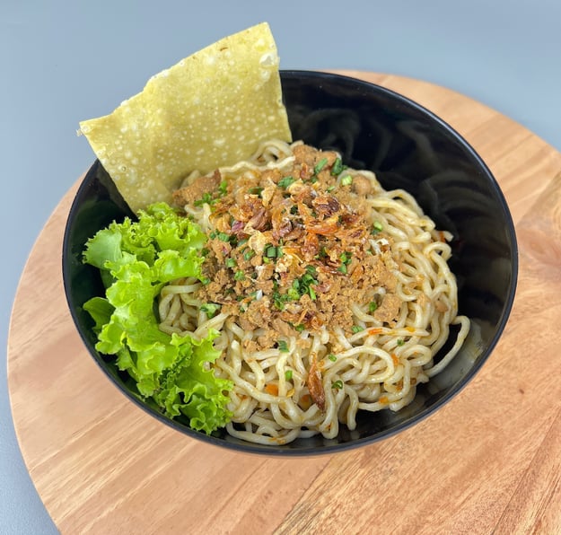 Mangkuk mie ayam dengan topping ayam, daun bawang, dan kerupuk pangsit di Depot Mie Ayam RATU