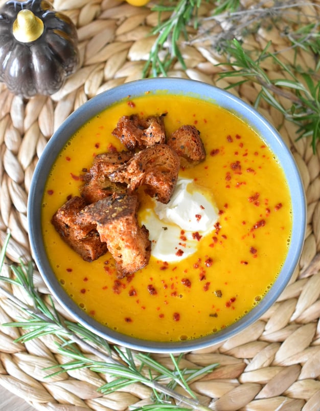 a bowl of pumpkin soup with croutons and cream 