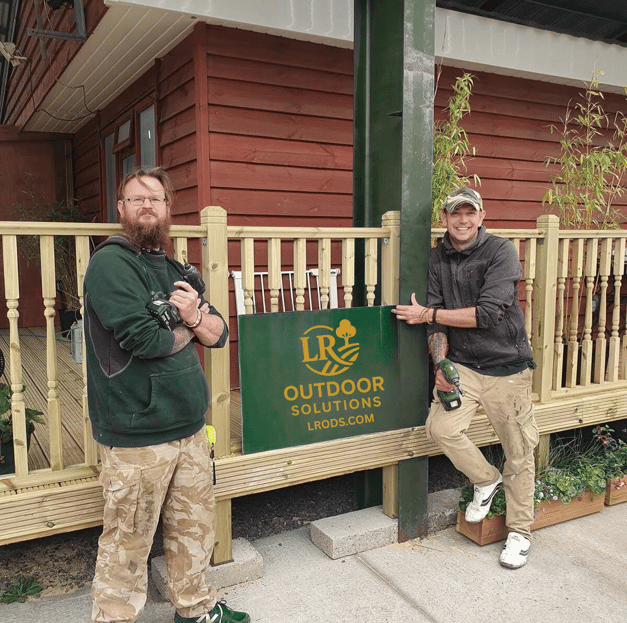 two men standing next to a sign that says outdoor