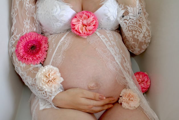 Femme enceinte, grossesse dans un bain de lait avec des fleurs autour d'elle 