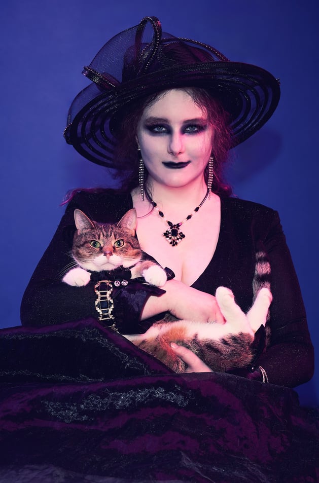 a woman in a witch costume wearing a black hat and holding a cat