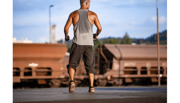 a man in a tank top running on a train track