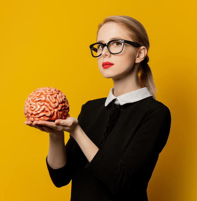 a blond woman with black glasses, holding a brain. she's on a yellow background.