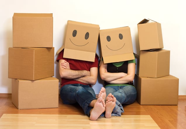 a man and woman sitting on the floor with boxes of boxes with smiley faces