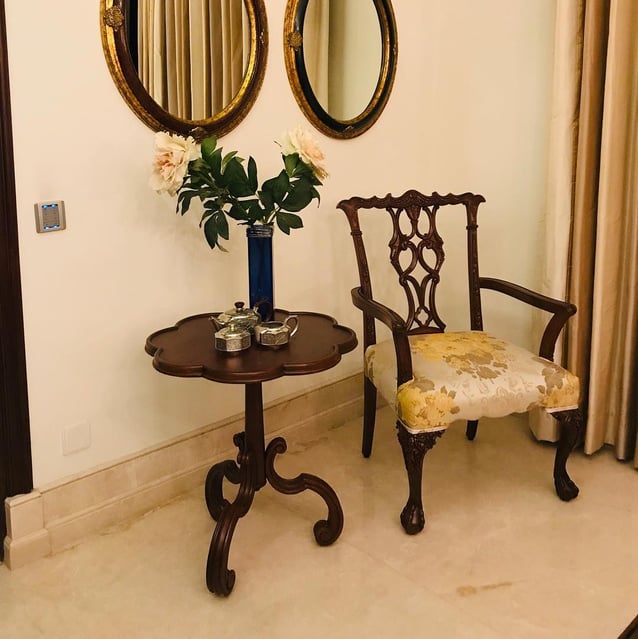 a wooden chair and a wooden table with a vase with flowers