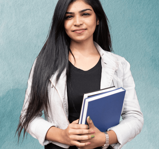 "Teacher standing with books in hand, ready to guide students in their learning."