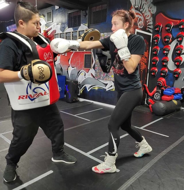 a woman in a boxing gloves is doing private boxing training with her coach