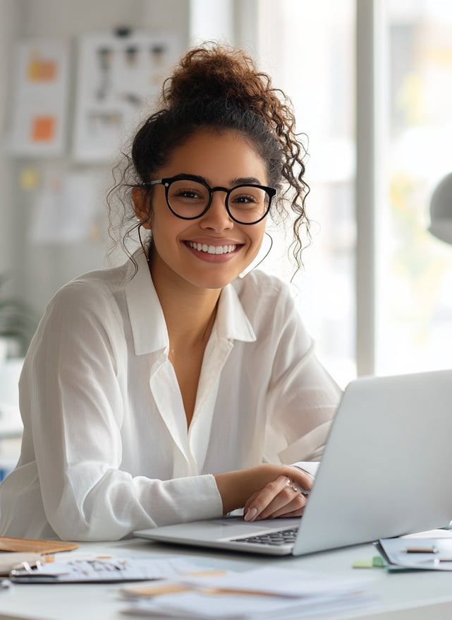 Emprendedora joven sonriente trabajando en laptop, representa productividad y liderazgo femenino en negocio digital en casa.