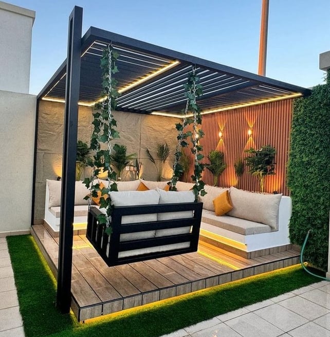 A modern outdoor lounge with a sleek pergola, LED lighting, built-in seating, and a hanging swing, c