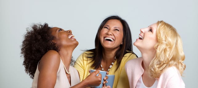 three women sitting on a couch and laughing