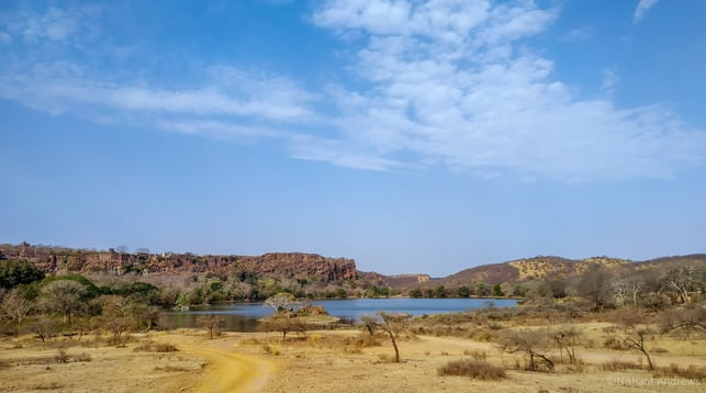 a dirt road with a lake and mountains in the background
