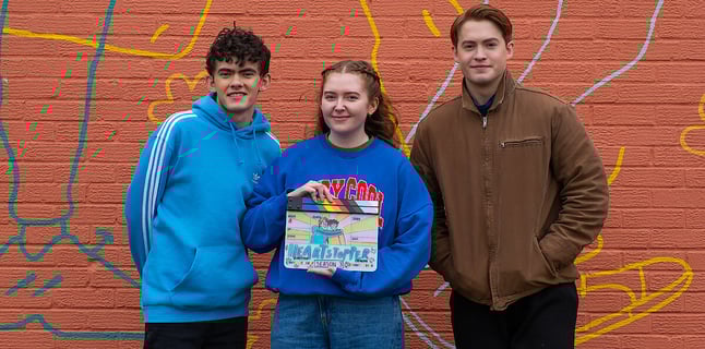 Alice Oseman holds heartstopper slate and poses with Joe Locke and Kit Connor