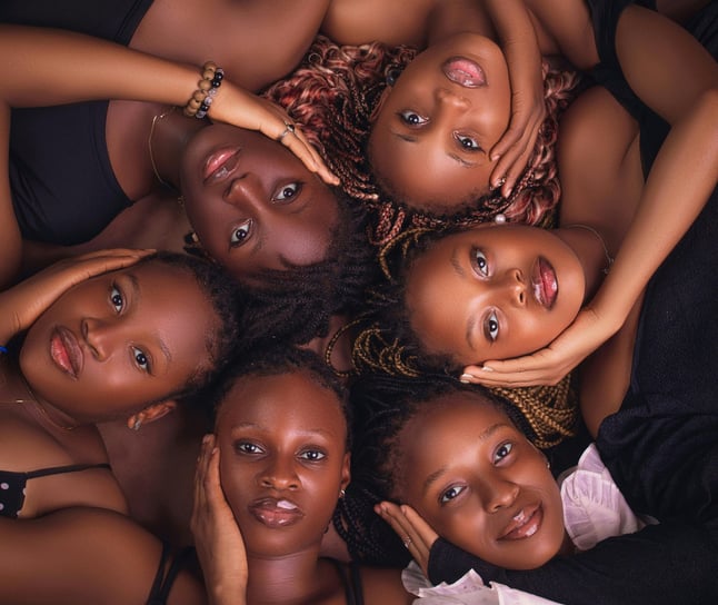 A group of Black women lying in a circle, symbolizing sisterhood, empowerment, and unity.
