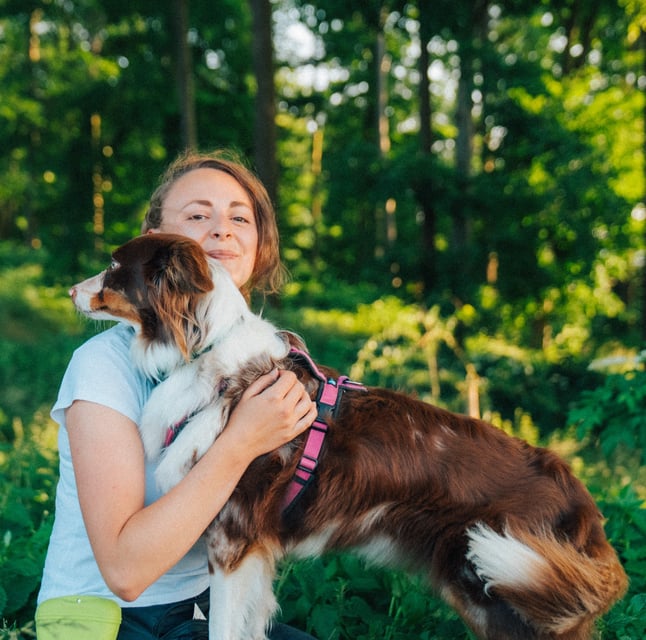 Toni hält Hund im Arm auf Baumstamm – achtsamer Moment im Waldbaden bei Takoda