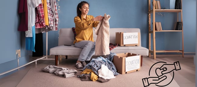 A woman sorting clothes for donation into labeled boxes in a cozy room, promoting sustainability