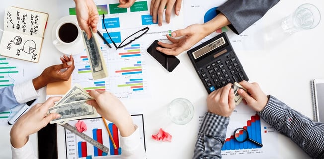 a group of people sitting around a table with money