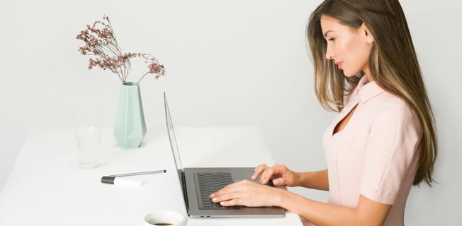 a woman in a pink dress is sitting at a table with a laptop