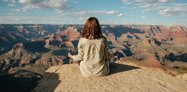 a woman sitting on a rock in the grand canyon