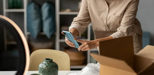 a woman in a beige shirt is holding a cell phone
