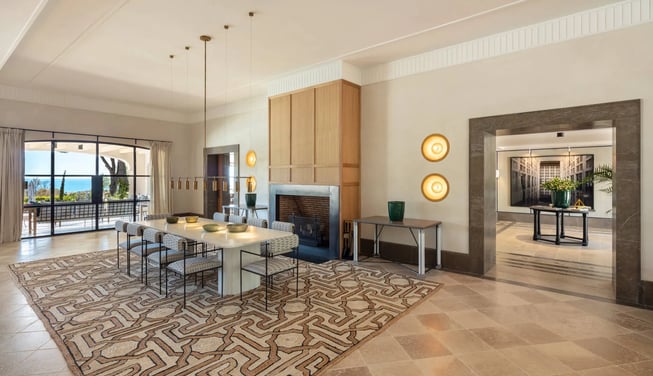 Dining room at Villa La Gratitud with fireplace, modern lighting, and terrace views toward the sea.
