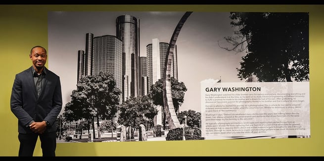 Photographer beside winning black and white photo at Detroit’s GMRENCEN exhibit.