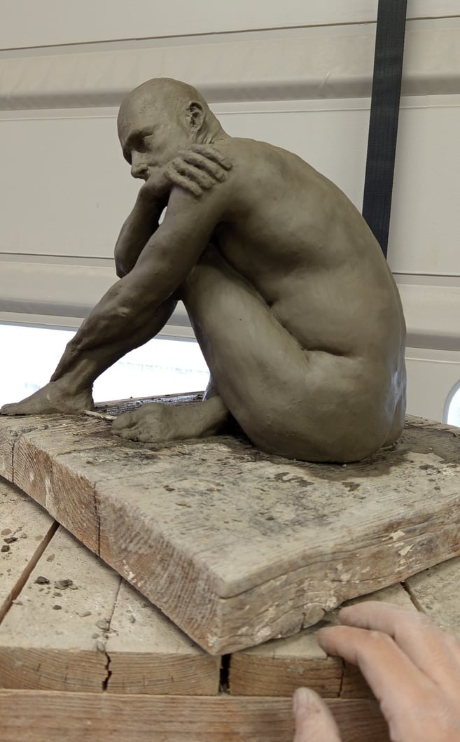a man is sitting on a table with a sculpture of a man