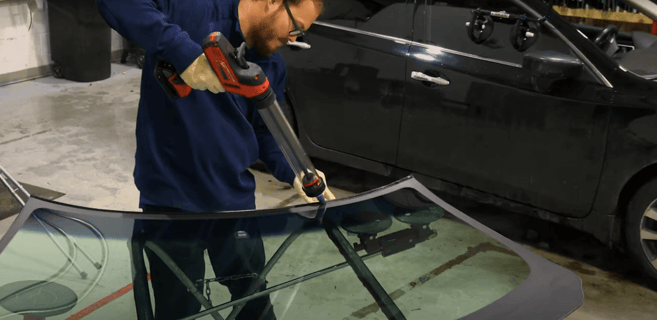 man caulking windshield in the shop
