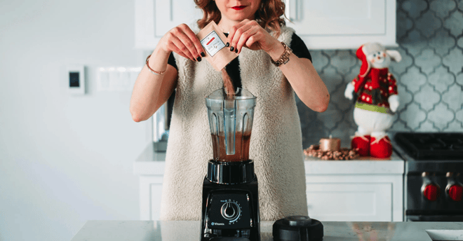mujer preparando un batido usando una licuadora negra