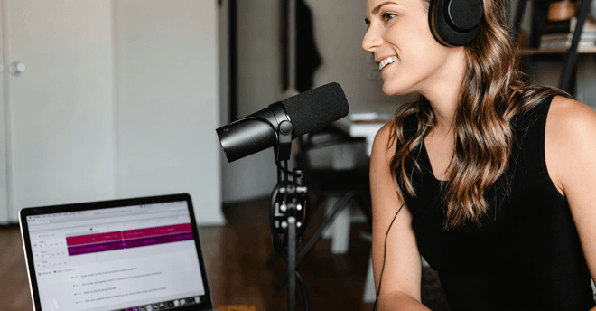 Mujer con audifonos y micrófono grabando un podcast