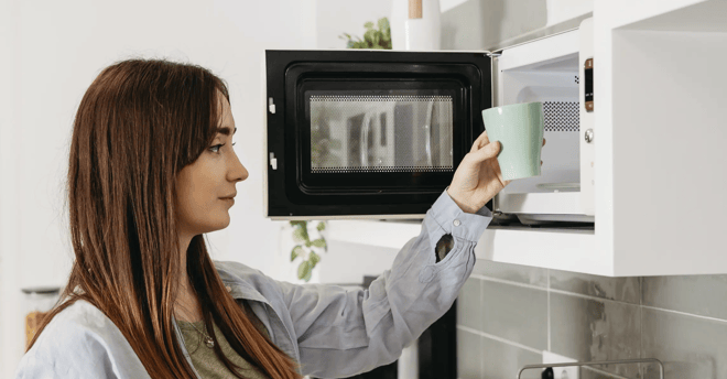 mujer calentando una taza en un microondas