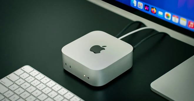 Apple Mac Mini blanca sobre una mesa con monitor y teclado