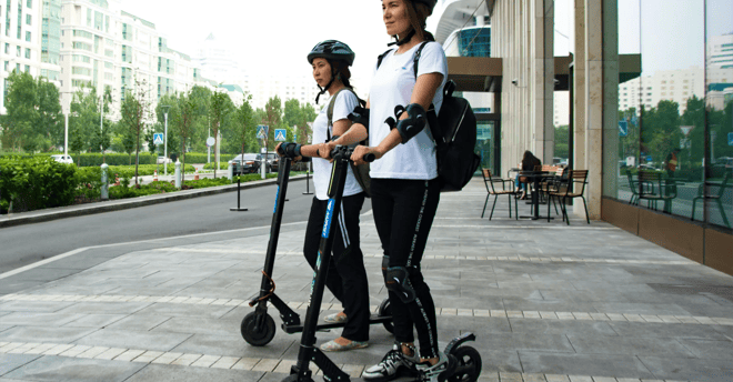 dos mujeres usando patinetes electricos en la calle