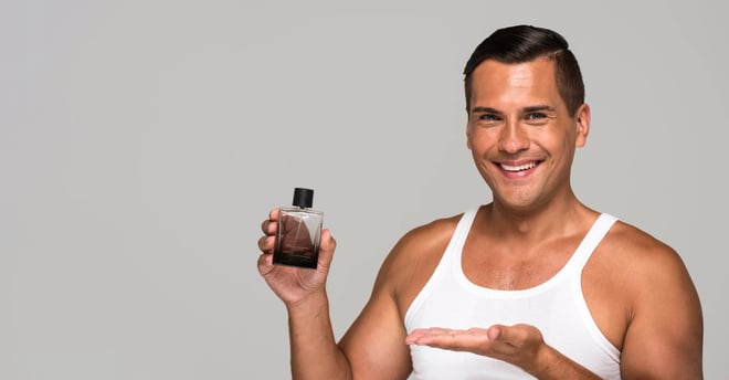 Hombre con playera blanca presentando un perfume