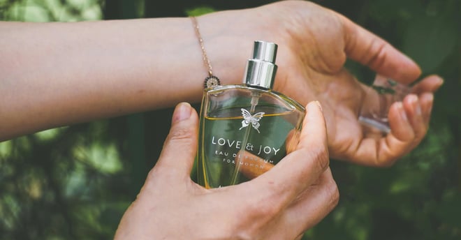 Mujer rociando perfume Love and Joy sobre su muñeca