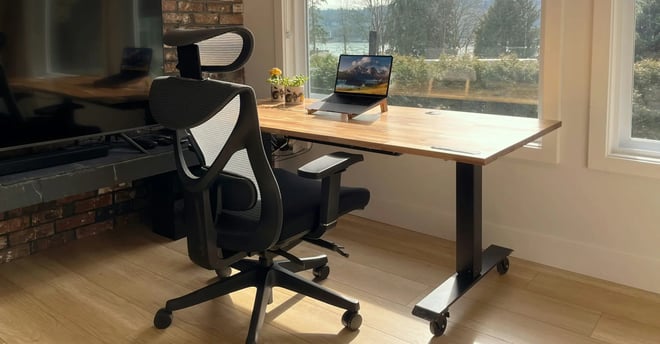 oficina con mesa de madera, una laptop y silla negra ergonomica