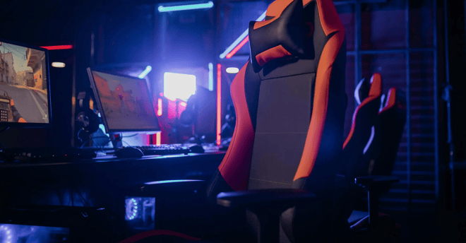 Silla Gaming con un escritorio en el fondo y pantallas de PC