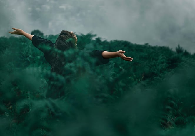 a woman standing in a field with her arms outstretched out