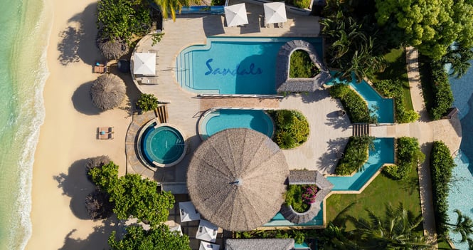 Coastal Vibe Travel - Explore Sandals Resorts a beach resort with a swimming pool and a sandy beach