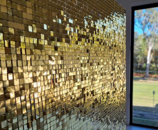 Gold shimmer wall glimmering for Maria's 60th birthday in Alexandra Hills, with the light dancing on its sequins.