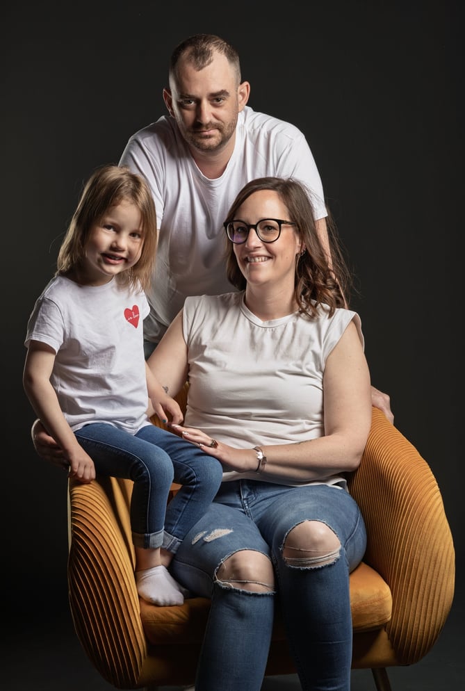 Couple avec un enfant, fauteuil jaune et fond noir