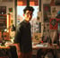 a man in glasses and a green shirt is standing in front of a desk with