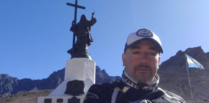a man in a white shirt and a cross - country Cristo Redentor Andes Chile