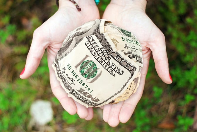 a person holding a ball with a dollar bill