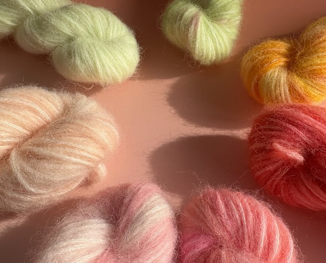 Håndfarvede garnfed i klare og pastelfarver – mohair, silke og merinould i orange, pink og blå.