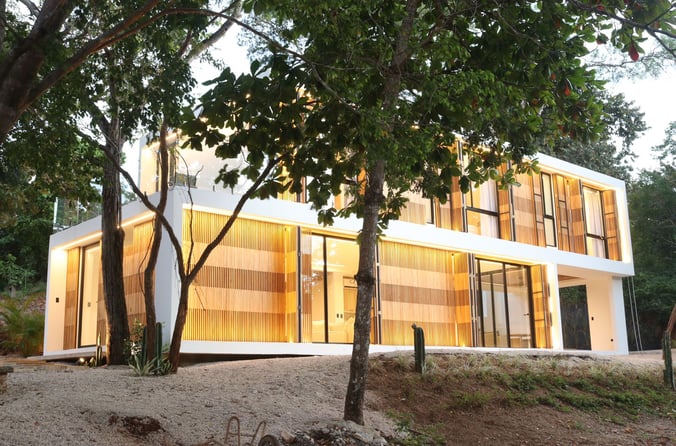 a house with a large glass window and a tree in Tamarindo, Costa Rica