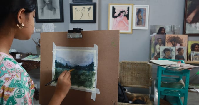 Student painting a watercolor in painting class