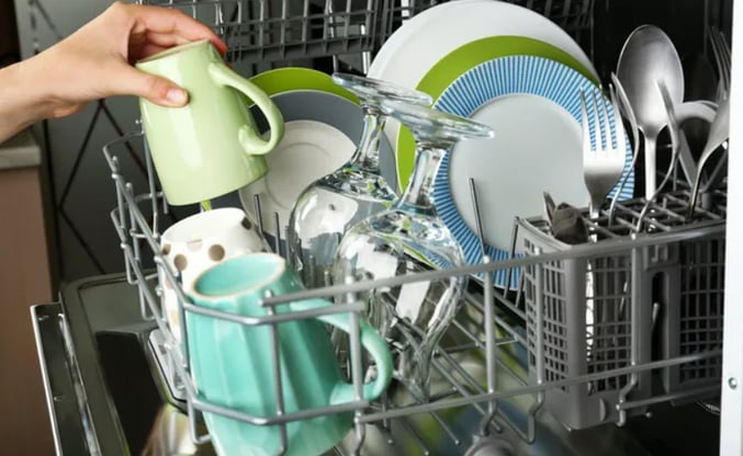 Plates, cups and glasses inside a dishwasher basket