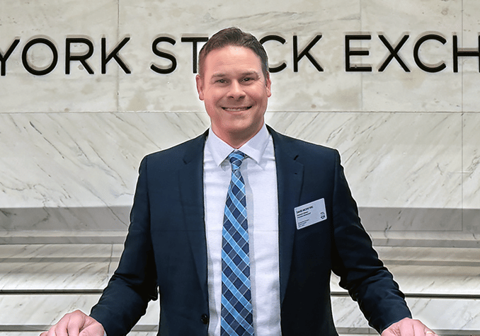a man in a suit and tie standing in front of a sign that says new
