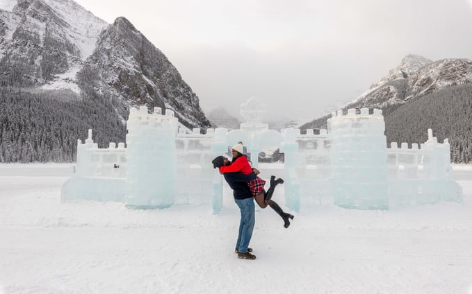 a man and woman in front of the lake louise ice castle 